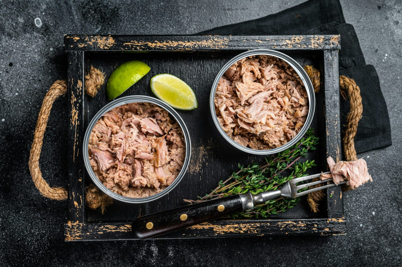 Open Can with Preserved tuna fillet meat. Black background. Top view